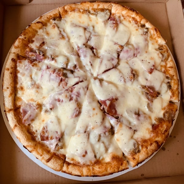A freshly baked, sliced Angelina's Pizza with melted cheese and various toppings in a cardboard box.