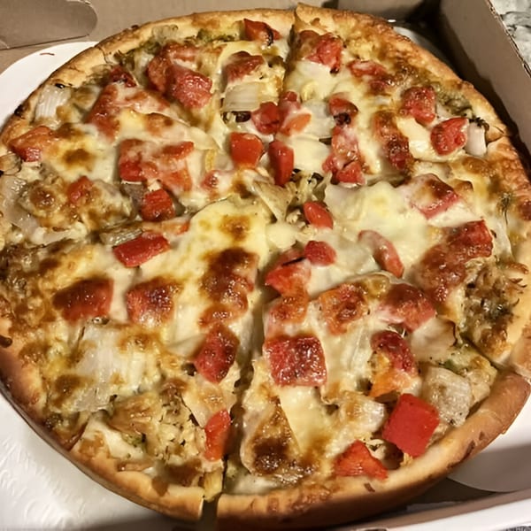 Angelina's Pizza with melted cheese, diced tomatoes, and onions in a cardboard box.