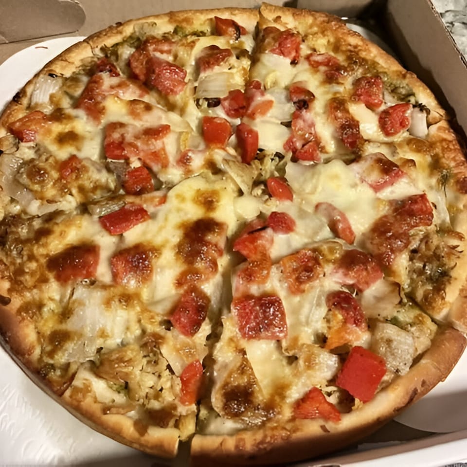 Angelina's Pizza with melted cheese, diced tomatoes, and onions in a cardboard box.